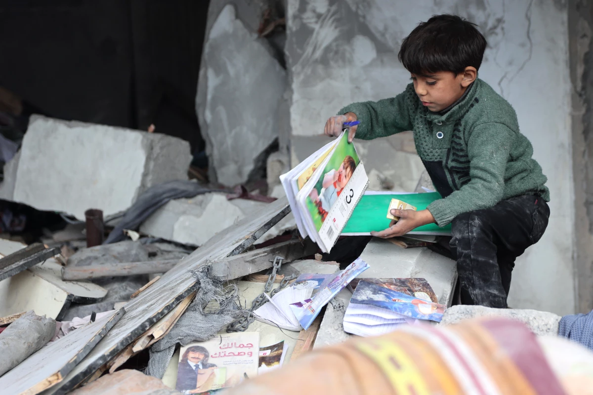 On Jan. 16, following a truce announcement amid the war between Israel and Hamas, a child recovers books from the rubble of a building hit in Israeli strikes the previous night in Jabalia, in the northern Gaza Strip.