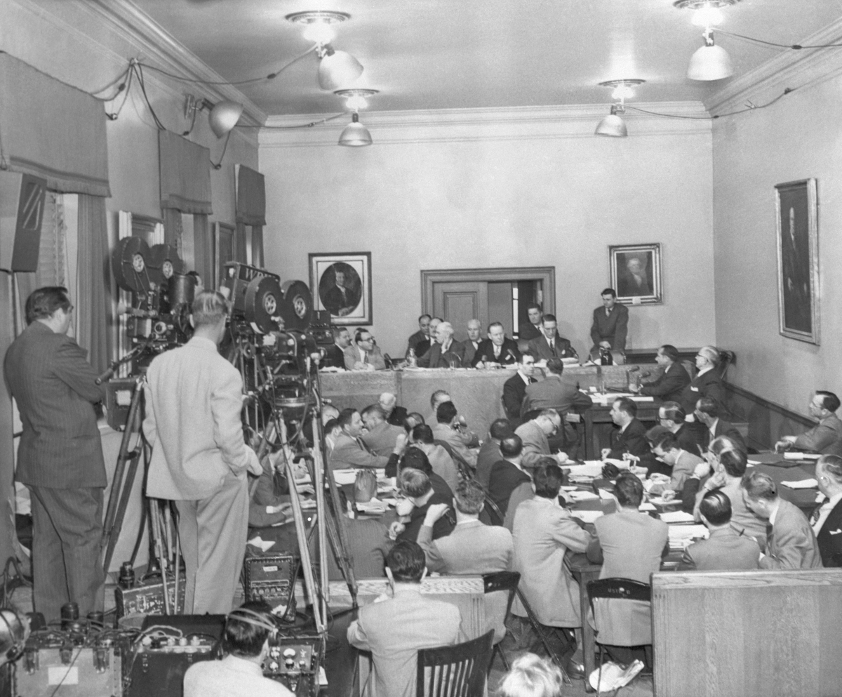 The packed scene in New York City as star witness Frank Costello (at witness table, right background, leaning forward) testified. Next to Costello is his lawyer, George Wolf. At the committee table are (left to right): Rudolph Halley, chief counsel for the committee; Sen. Charles Tobey (R-N.H.); Sen. Herbert O'Conor (D-Md.); and Sen. Estes Kefauver (D-Tenn.), the committee chairman.