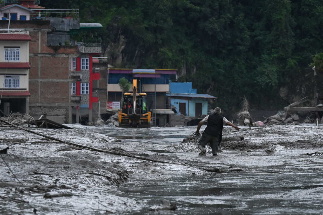 A resident walks along a street covered in mud following flash floods and a landslide disaster in Devighat, in Nepal's Nuwakot district, on Wednesday. A massive flood and landslide disaster wiped out entire settlements.