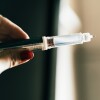 One hand holds a syringe.