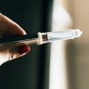 A hand holds a syringe.