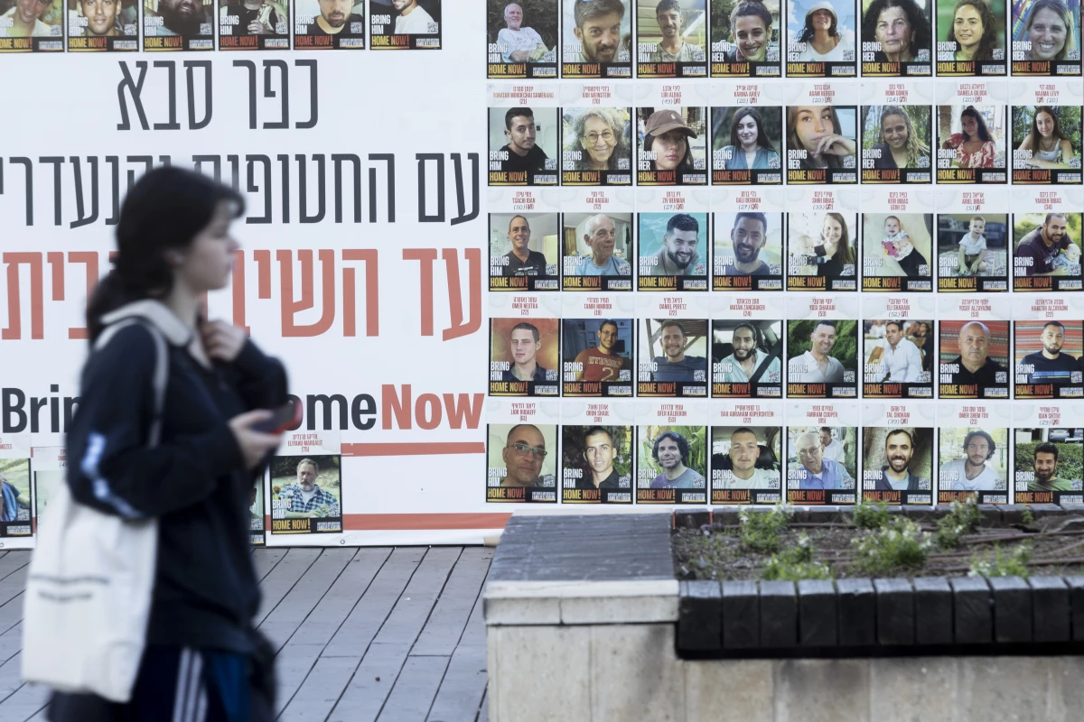 A woman passes a wall on Monday in Kfar Saba, Israel, covered with photos of hostages kidnapped to the Gaza Strip during the Oct. 7, 2023, Hamas-led attack.