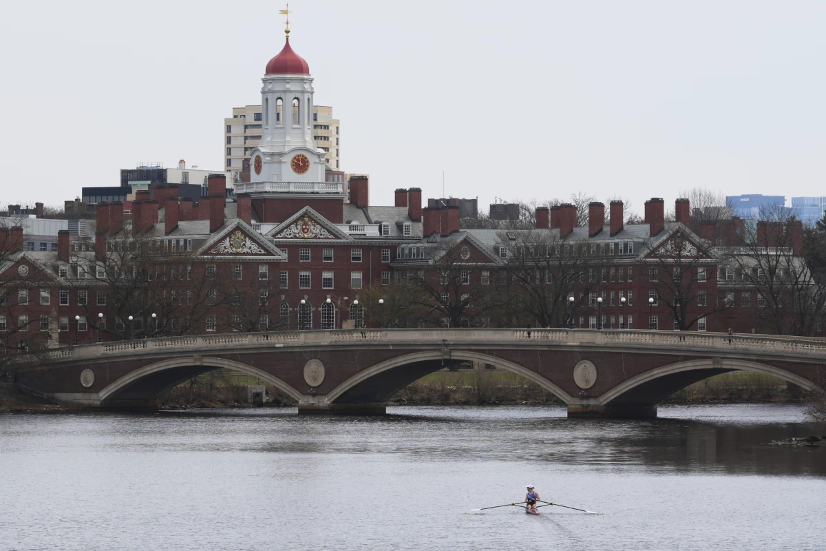 A sculler rows down the Charles River near Harvard University, at rear, on April 15, 2025, in Cambridge, Mass.