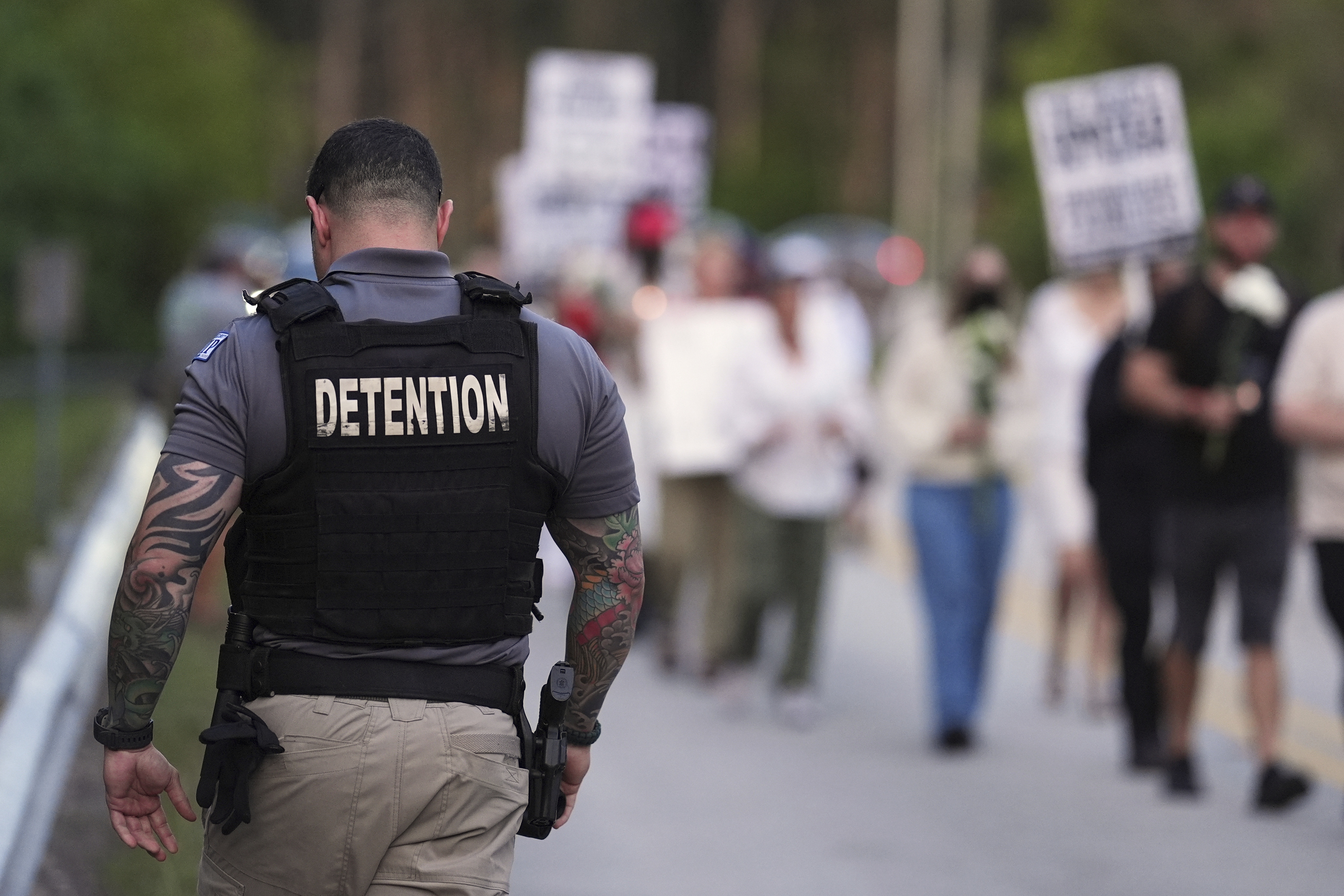 A Krome Detention Center officer patrols as people hold a vigil on May 24 to recognize those who have died in U.S. Immigration and Customs Enforcement custody as well as those affected by mass deportations, outside Krome Detention Center in Miami. (AP)