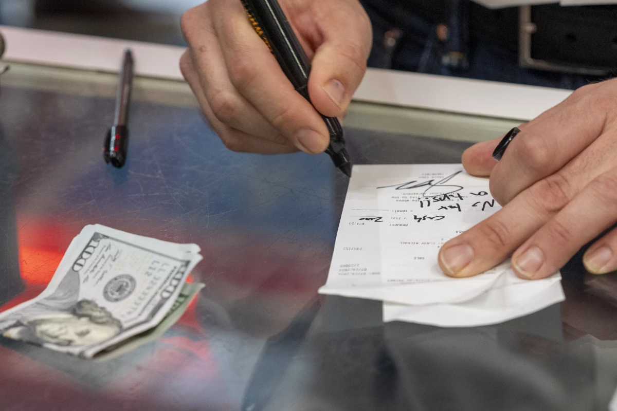 Republican vice presidential candidate Sen. JD Vance, R-Ohio, signs a check 'no tax on tips!!' as he leaves $200 in cash for a gratuity at the Park Diner, in Waite Park, Minn., on July 28.