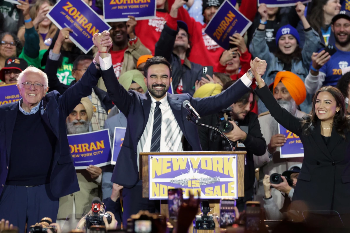 New York City Mayor-elect Zohran Mamdani holds hands with Sen. Bernie Sanders and Rep. Alexandria Ocasio-Cortez at a campaign rally in October. All three identify as democratic socialists.