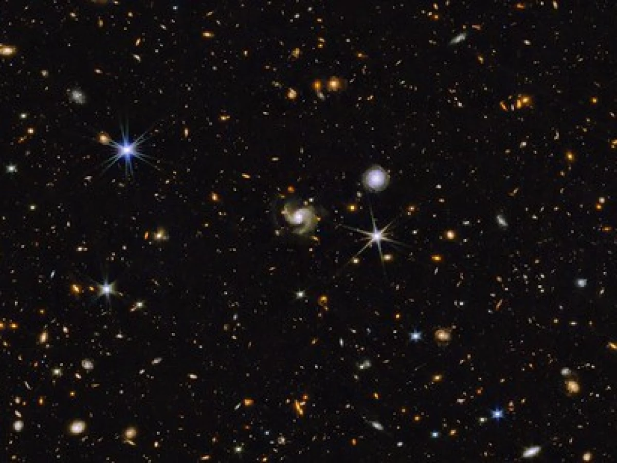This multi-wavelength image from NASA shows a universe full of galaxies that are various shapes, colors and sizes. Most are small while a handful are somewhat larger. A few stars are also scattered across the image.
