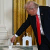 President Trump stands near models of his arch during an October 2025 event with White House ballroom donors. The administration's proposed design and location for the structure have changed little since then.