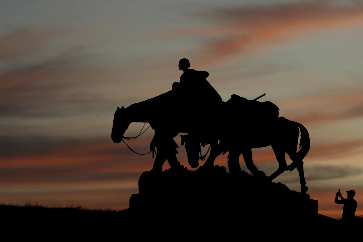 A man takes a photo as he visits the Pioneer Mother Memorial as the sun sets Thursday, March 19, 2020, in Kansas City, Mo.