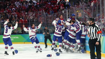 MILAN, ITALY - FEBRUARY 22: Jack Hughes \#86 of Team United States celebrates with teammates after scoring the game-winning goal in overtime during the Men's Gold Medal match between Canada and the United States on day 16 of the Milano Cortina 2026 Winter Olympic games at Milano Santagiulia Ice Hockey Arena on February 22, 2026 in Milan, Italy.