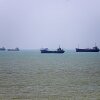In this photo, six vessels float on the water, anchored along the Strait of Hormuz.