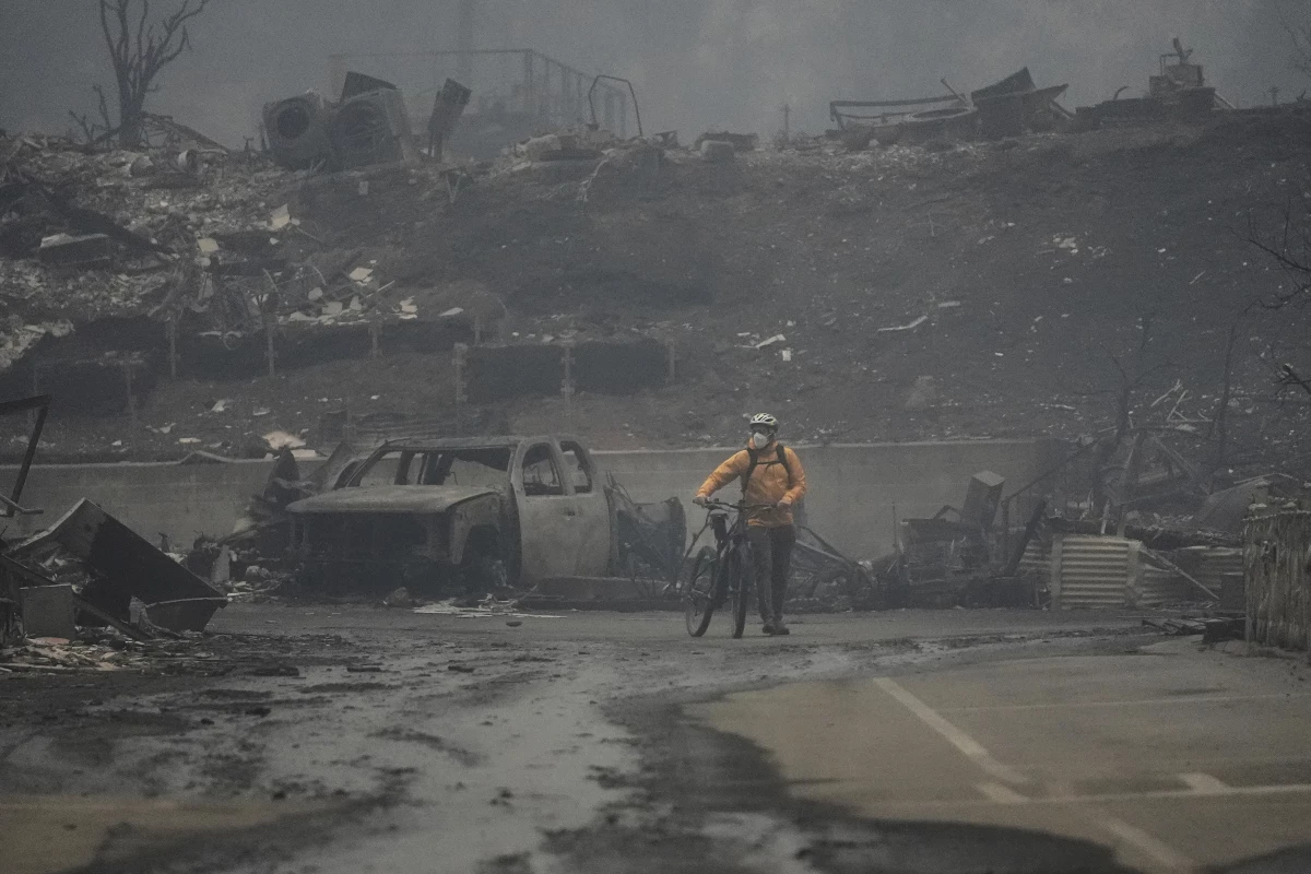 A man is seen walking his bike among the ruins left behind by the Palisades fire in the Pacific Palisades neighborhood on Wednesday.