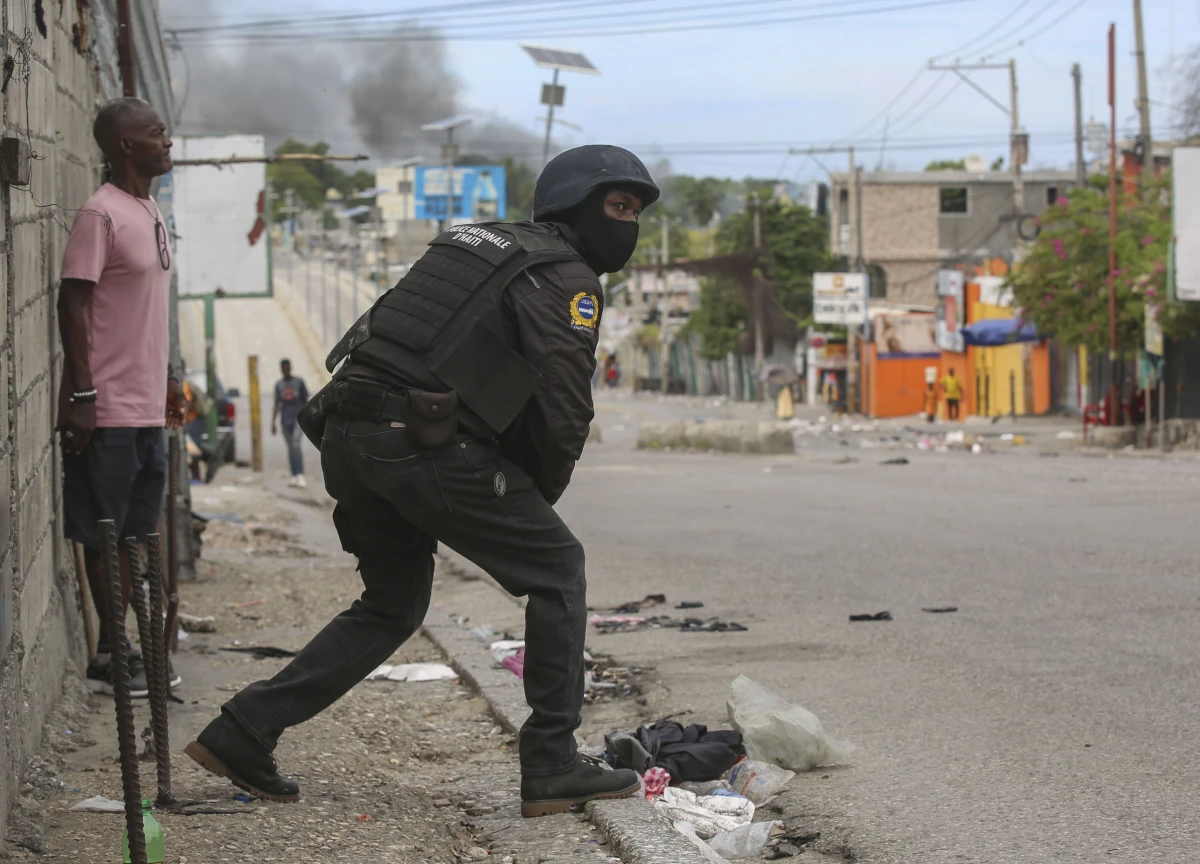 A police officer looks on during an exchange of gunfire between gangs and police in Port-au-Prince, Haiti on Monday.