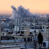 A person standing on the roof of a building looks at a plume of smoke rising after a strike on the Iranian capital, Tehran, on Tuesday.