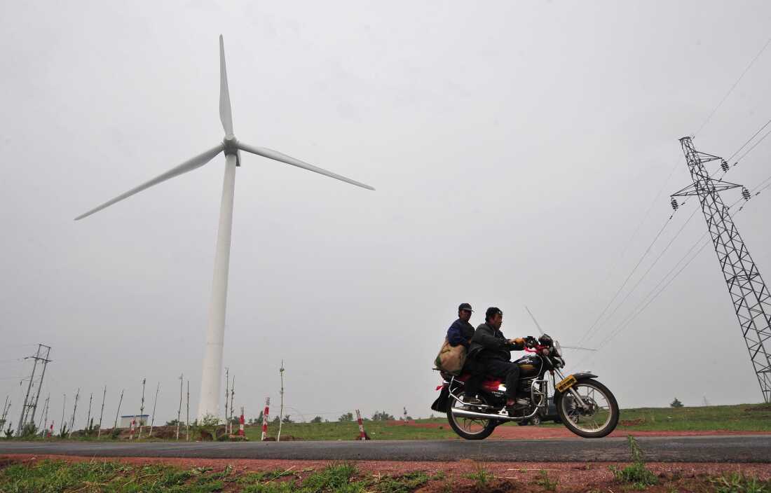 In a picture taken on June 16, 2009, commuters on a country road ride past a wind farm developed by state-owned China Energy Conservation Investment Corp in Zhangbei, north of Beijing in Hebei province.