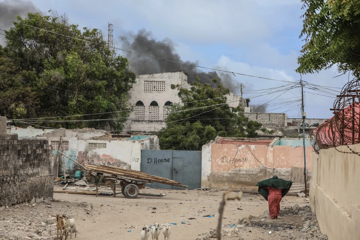 A woman reacts while walking in a street as smoke billows in the background from an explosive-laden car diffused by the Somali police in Mogadishu on Saturday.