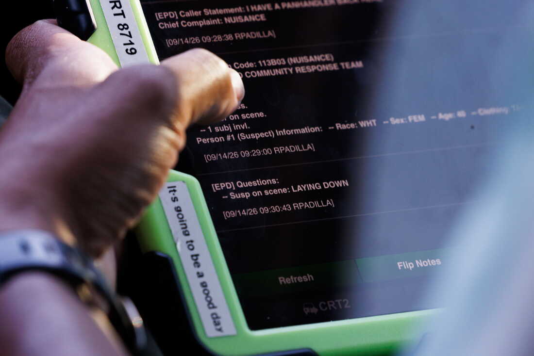 This photo shows a handheld device with Rob Crisp's left hand holding the left side of it. The device's screen displays dispatch notes for a person trespassing at a business.