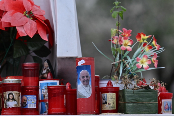 A candle with a picture of Pope Francis is set at the bottom of a statue of Pope John Paul II at the Gemelli hospital where Pope Francis is hospitalized for tests and treatment for bronchitis in Rome, on Feb. 15.