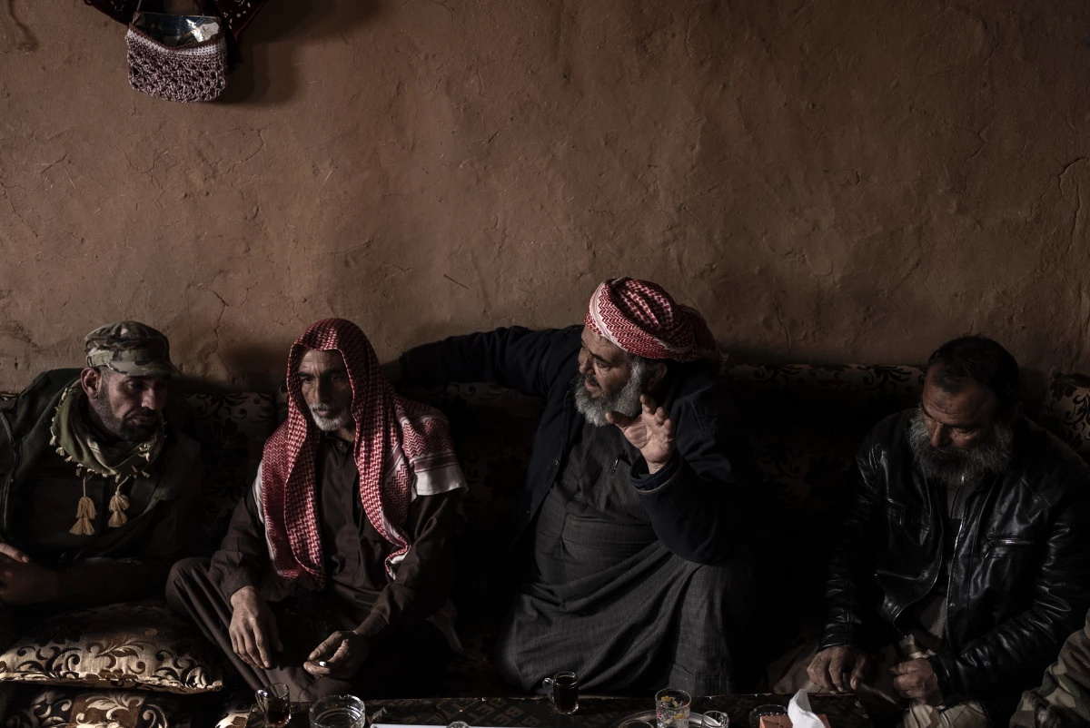 Fawaz al-Taleb gestures as he speaks with other Syrian men gathered in the living room of a home in the Rukban camp for displaced people, on Dec. 14.