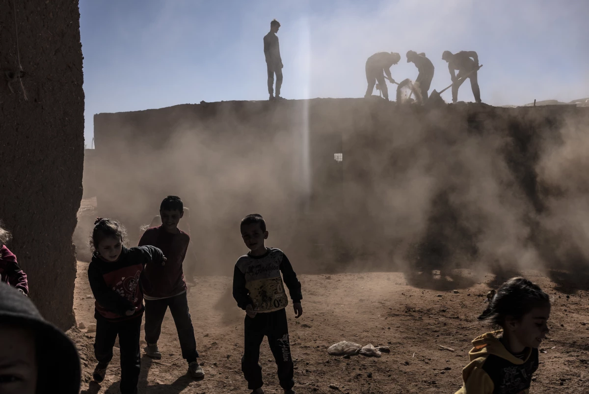 Syrian children play while adults are on the roof dismantling a house at the Rukban camp for displaced people in southern Syria, Dec. 14.
