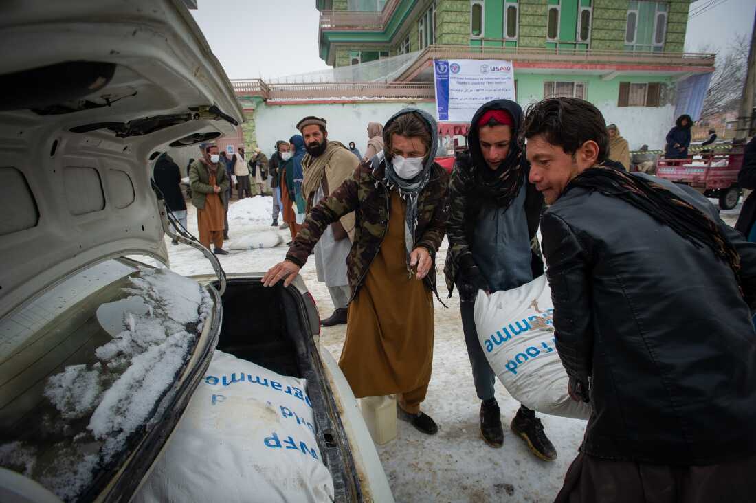 PUL-E ALAM, AFGHANISTAN -- JANUARY 17: Afghan men load sacks of flour into a car for transport, as the UN World Food Program (WFP) distributes a critical monthly food ration, with food largely supplied by the US Agency for International Development (USAID), to 400 families south of Kabul in Pul-e Alam, Afghanistan, on January 17, 2022. This food delivery to Logar province comes as the UN warns that 23 million Afghans, more than half the population, are on the verge of famine, following a severe drought and as winter deepens, while the US and World Bank have only partially released funds frozen when the Taliban took control of Afghanistan in August 2021. The UN has made an emergency appeal for $5.5 billion to feed the hungry and forestall further economic collapse.