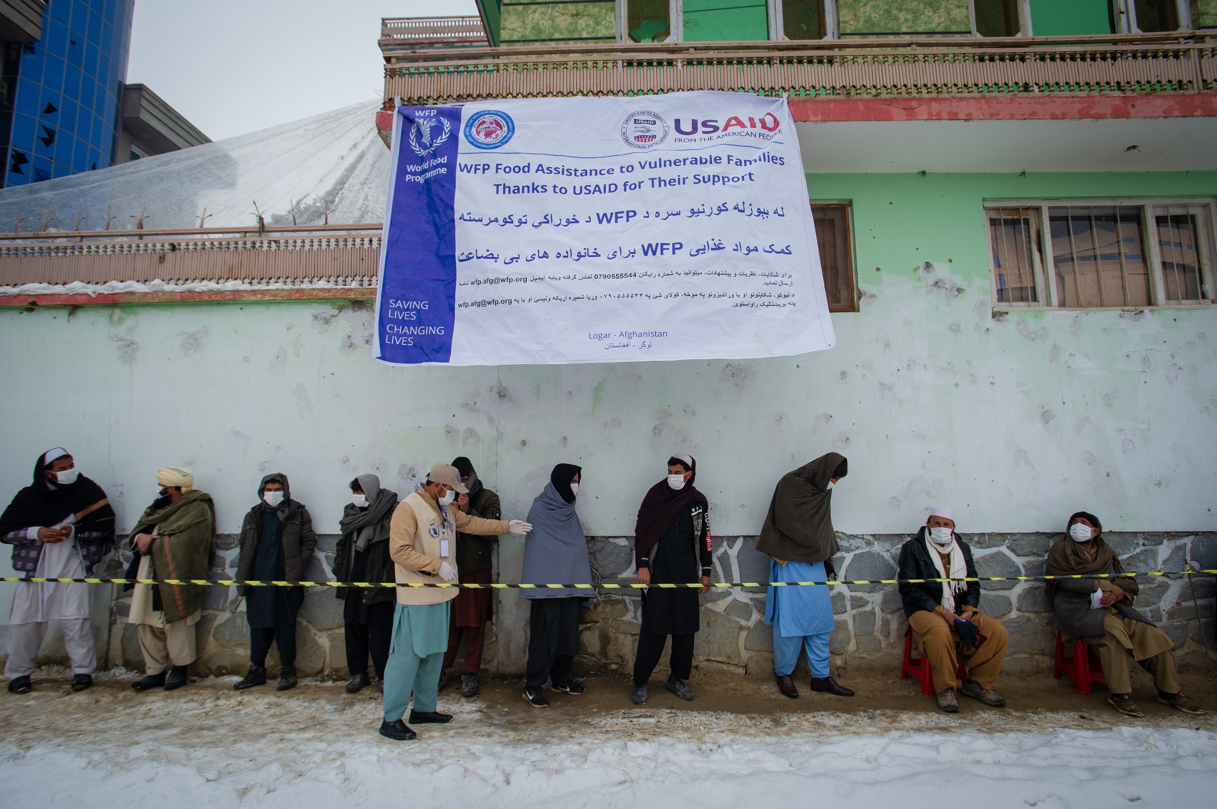 Afghan men wearing masks to prevent the spread of COVID-19 line up as the U.N.