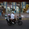 Des drapeaux israéliens sont accrochés dans un magasin tandis qu'un cycliste transportant des enfants passe, le mercredi 28 octobre 2026, à Tel Aviv, en Israël, au lendemain des élections générales israéliennes.