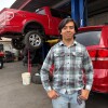 Guadalupe Higuera stands in front of trucks being repaired at his family's shop in Phoenix.