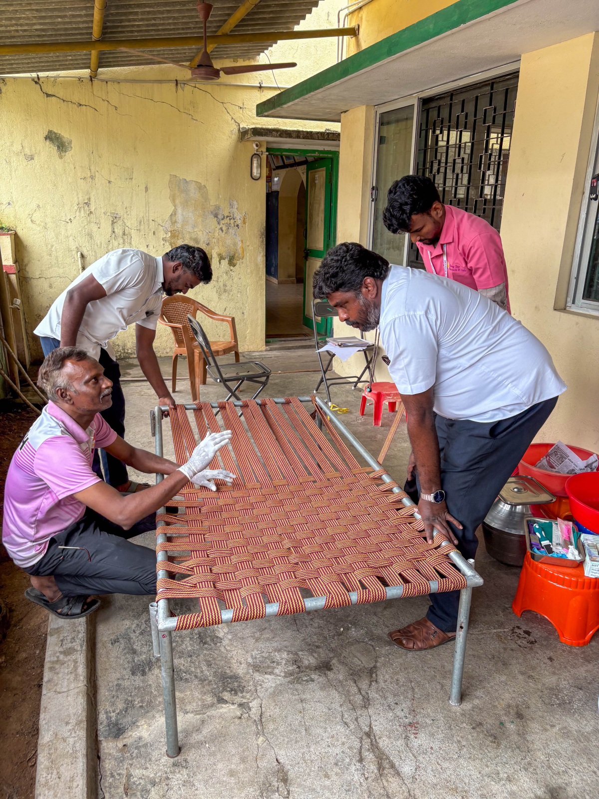 Employees of the Rising Star Outreach charitable group, which provides medical care and other services to leprosy colonies, make an open weave cot for a resident. The air flow in this type of bed helps protect wounds that linger long after leprosy is cured.