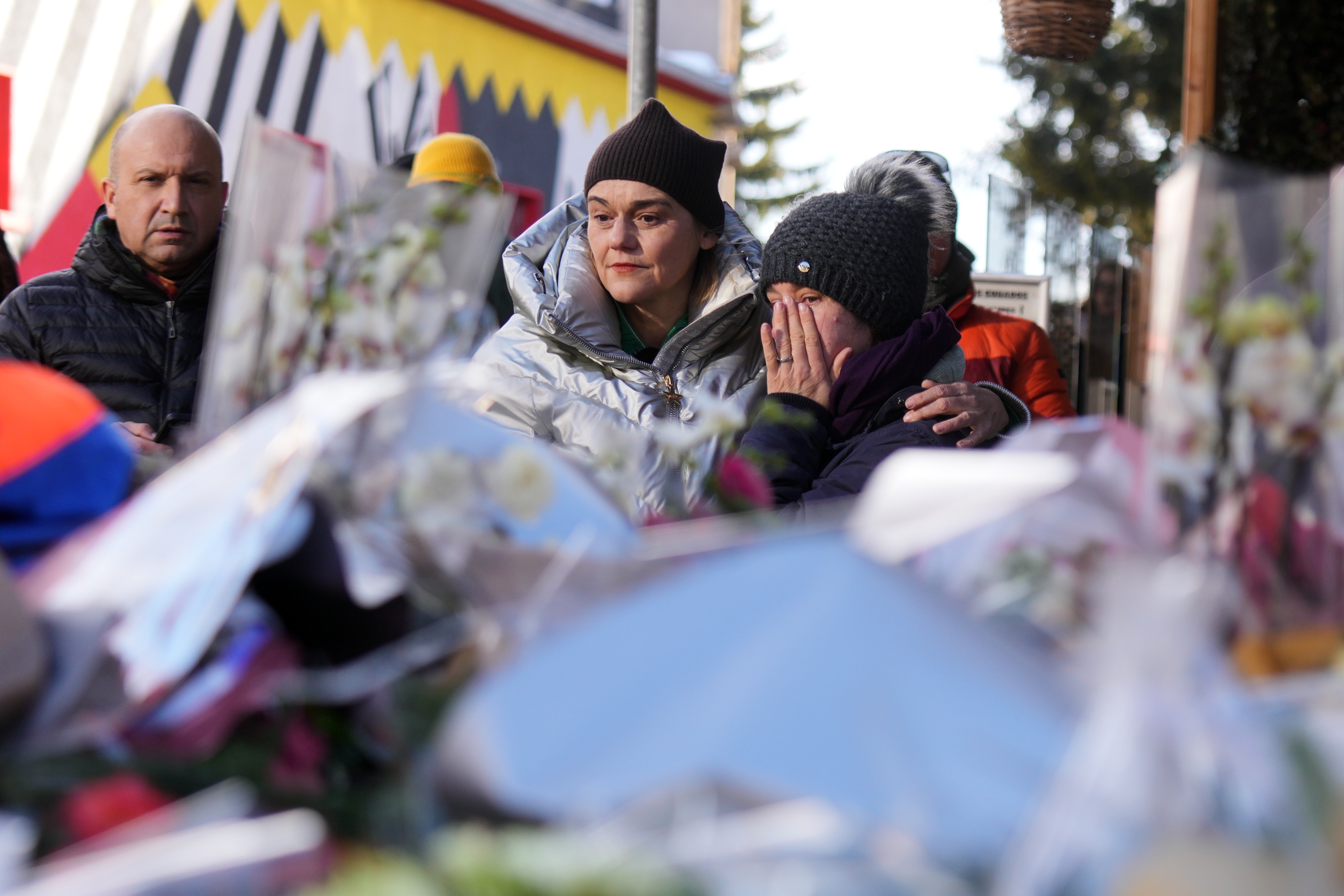People mourn behind flowers and letters near the sealed off Le Constellation bar, where a devastating fire left dead and injured during the New Year's celebrations in Crans-Montana, Swiss Alps, Switzerland, on Friday, Jan. 2. (AP)