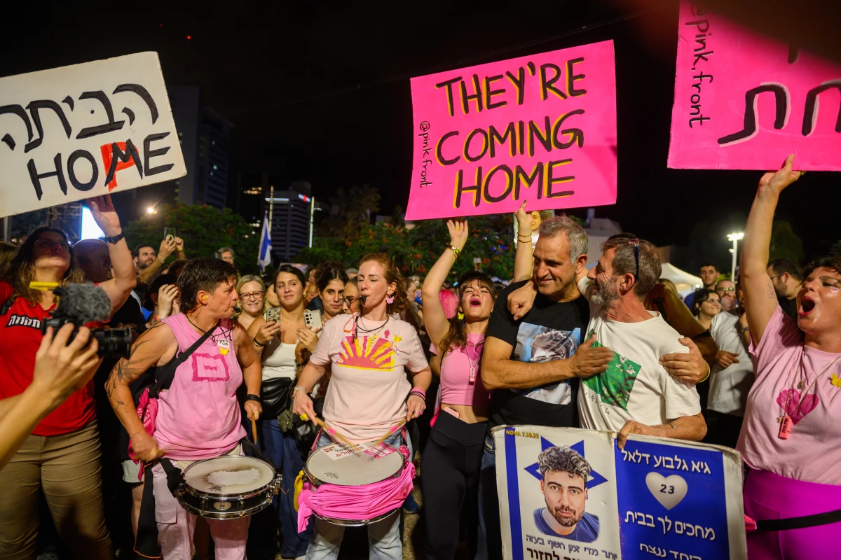Michel Illouz (L), father of Guy Illouz, and Ilan Dalal, father of hostage Guy Gilboa Dalal (R), embrace and react next to protestors cheering and holding signs that read, 'they're coming home' in Hostages Square, Tel Aviv, on Oct. 11th