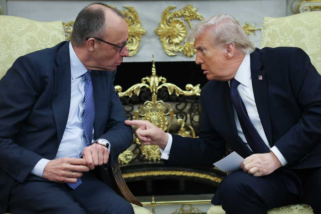 President Trump, on the right side of the frame, and German Chancellor Friedrich Merz, on the left side, sit on armchairs in the White House on March 3. They have turned in their armchairs to face one another, and Trump is tapping Merz's left elbow with his right index finger.
