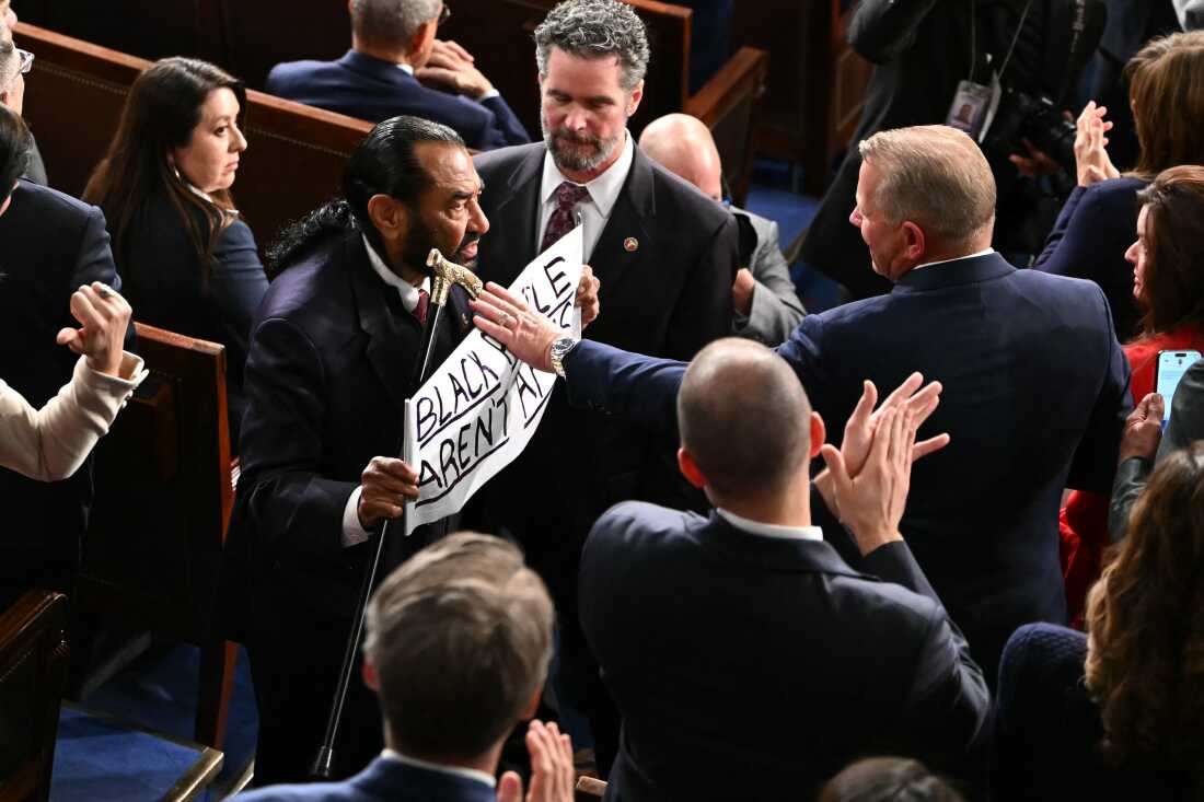 U.S. Rep. Al Green, D-Tx., exits as he holds a sign reading "Black people aren't apes" during President Trump's State of the Union address in the House Chamber of the US Capitol in Washington, DC, on February 24, 2026.