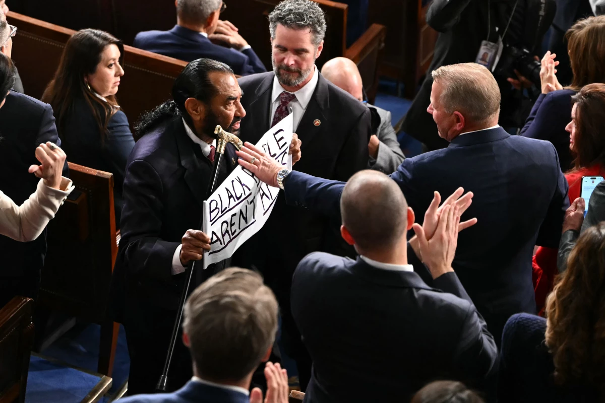 U.S. Rep. Al Green, D-Tx., exits as he holds a sign reading 'Black people aren't apes' during President Trump's State of the Union address in the House Chamber of the US Capitol in Washington, DC, on February 24, 2026.