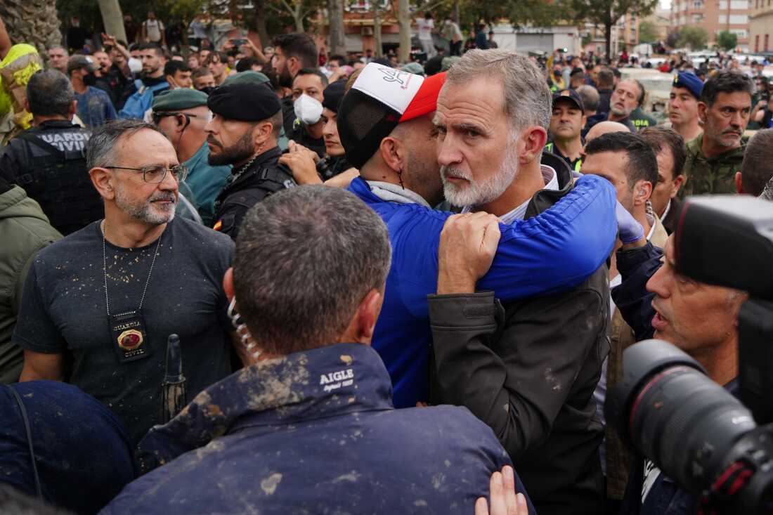 King Felipe VI of Spain is hugged by a man as other angry residents heckled him during his visit to Paiporta, in the region of Valencia, eastern Spain, on November 3, 2024, in the aftermath of devastating deadly floods.