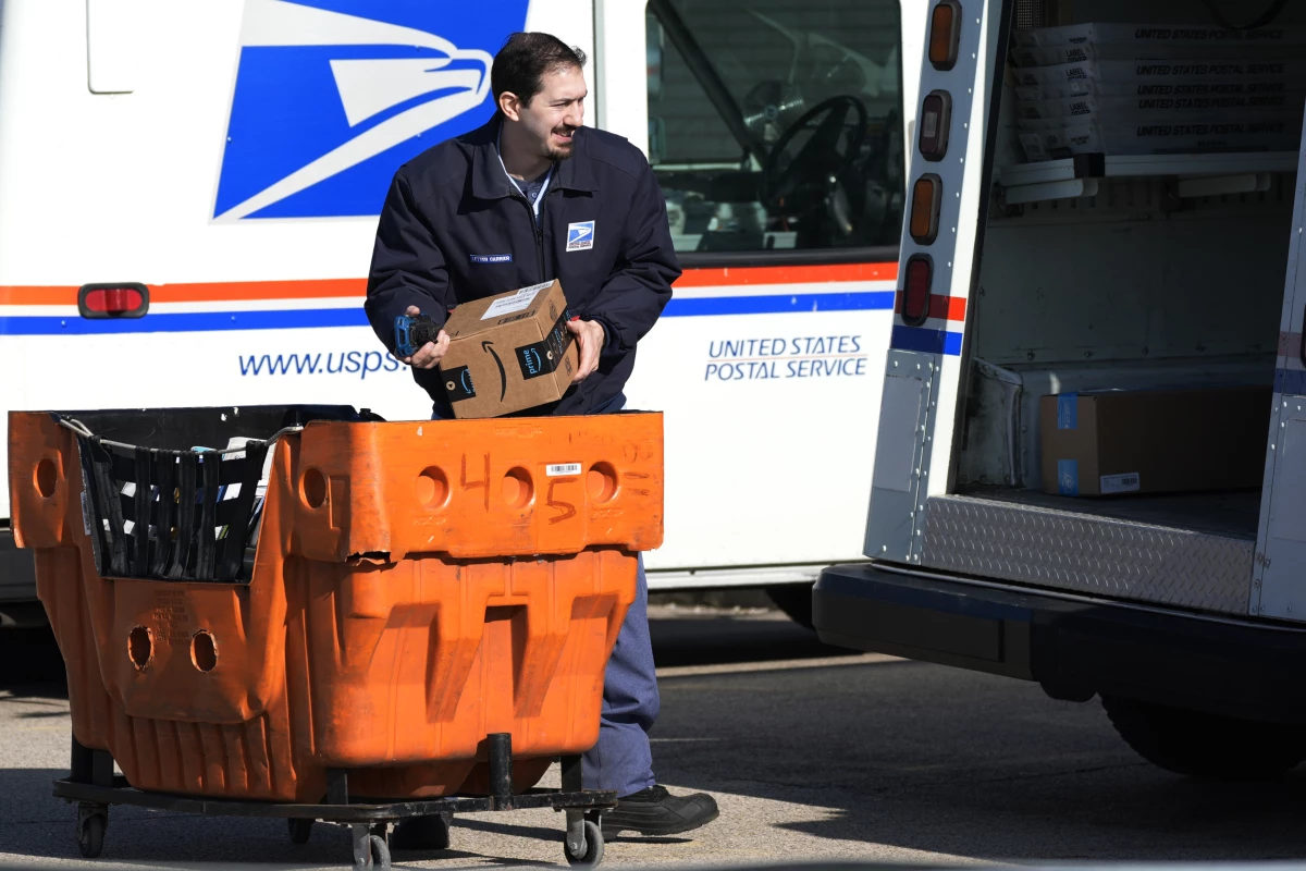 A U.S. Postal Service employee is shown loading parcels outside a post office in Wheeling, Ill., on Jan. 29, 2024.