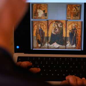 A journalist browses the Messina museum website showing a picture of the Early Renaissance painter Antonello da Messina's artwork where three of the five panels belonging to the Polyptych of San Gregorio and the double-sided panel with the Madonna and the Christ in Pietà, stolen from the Sicilian museum on Aug. 15, in Rome, Sunday, Aug. 16, 2026.