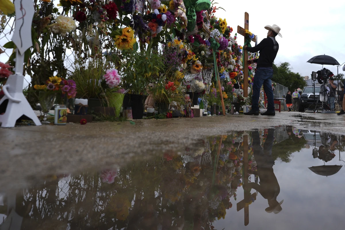 Roberto Marquez places a cross at a memorial wall for flood victims, Sunday, July 13, 2025, in Kerrville, Texas.