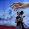 Visitors walk past a display depicting artificial intelligence and a human hand at the China International Supply Chain Expo in Beijing on June 22.