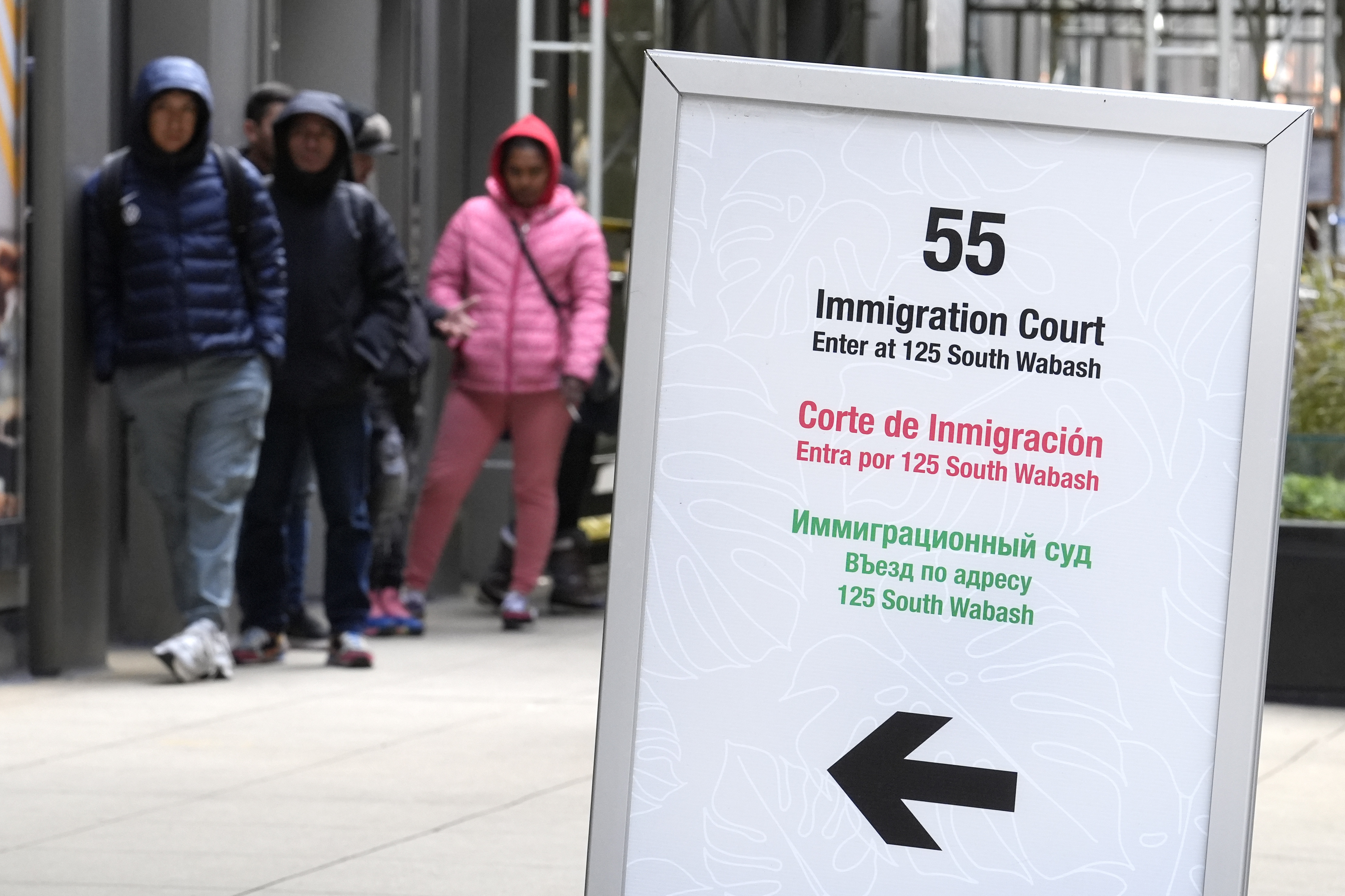 People wait in a line before being led into a downtown Chicago building where an immigration court presides on Nov. 12, 2024, in Chicago. (AP Photo/Charles Rex Arbogast)