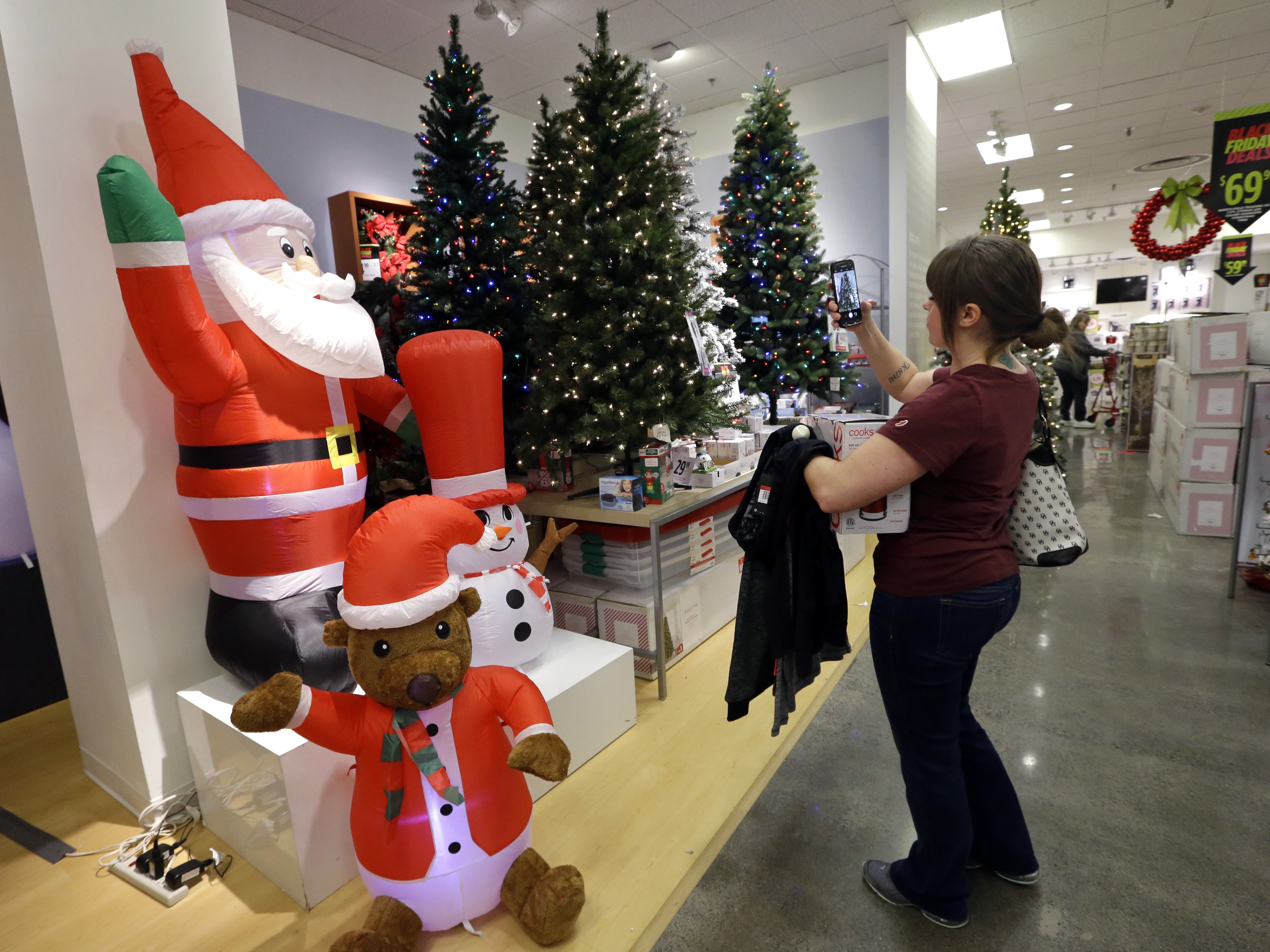 A woman takes photos of artificial Christmas trees while shopping at a J.C. Penney store, Friday, Nov. 24, 2017, in Seattle.