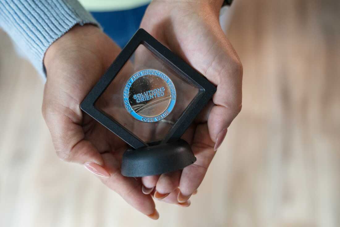 Stephani Cherkaoui holds an award she received during her time at the Agriculture Department. The coin-shaped award says around its border: "Food Safety and Inspection Service Core Value" and in the center it says: "Solutions Oriented."