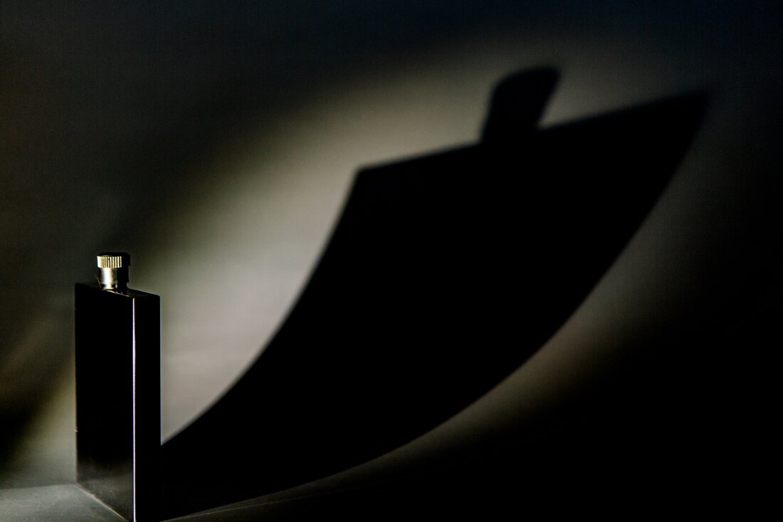 Photograph shows a metal flask casting a huge shadow that looks like a looming monster, symbolizing hangover anxiety.
