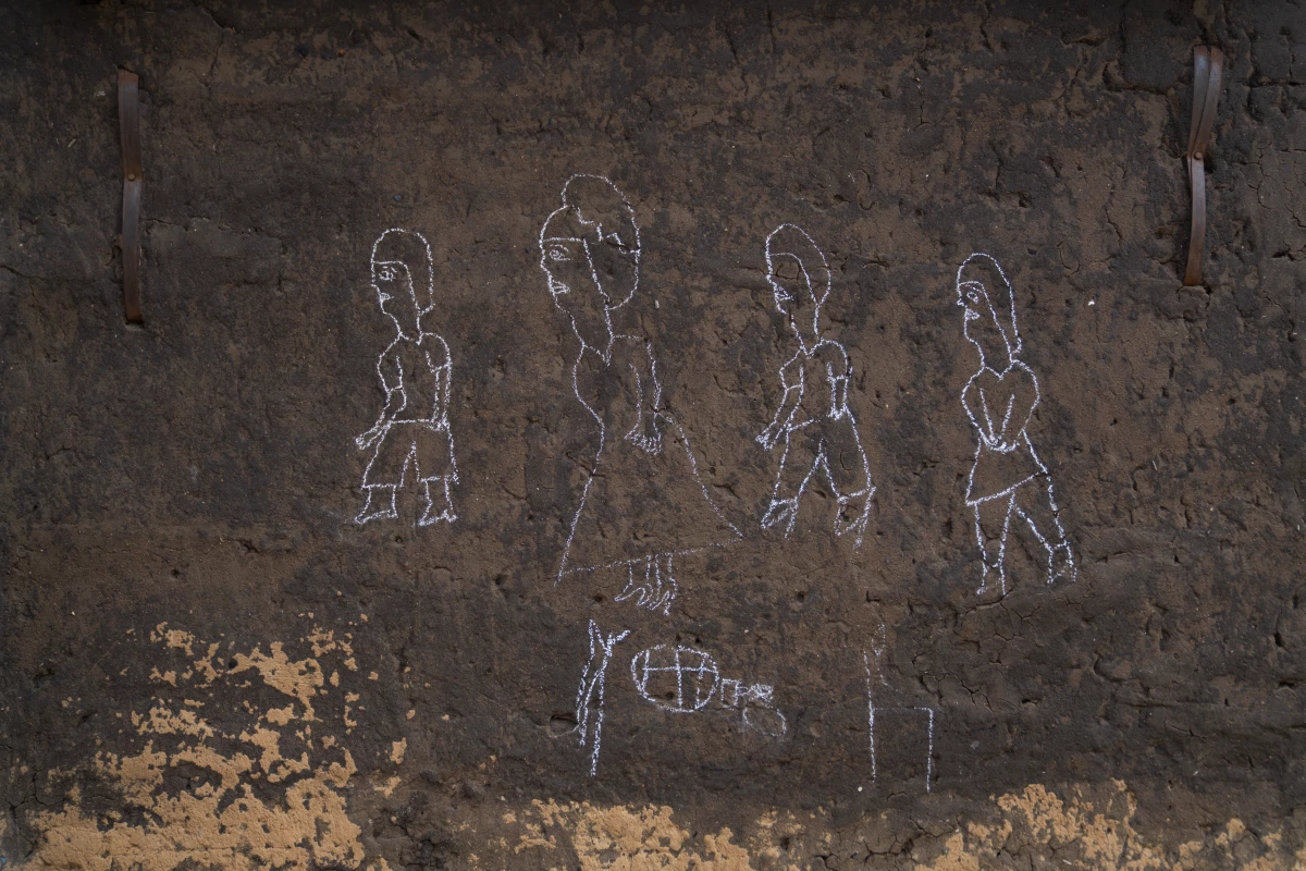 Santa Angwech's son drew a picture of their family on a mud wall of their home.
