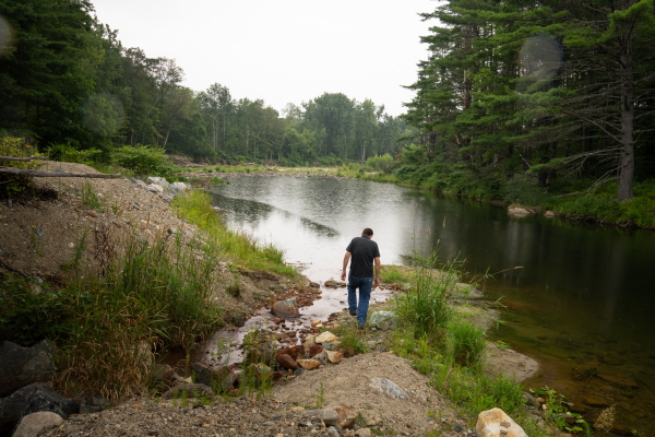 Chris Hughes, Assistant Water/Wastewater Operator for the towns of Cavendish and Proctorsville, VT , walks near where water is discharged into part of the Black Rivier.