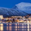 Dusk falls over snowy mountains overlooking the Arctic Cathedral and houses mirrored in the icy fjord in Tromsø, Norway. Although this city is north of the Arctic Circle and experiences polar night for two months out of the year, its residents tend to see winter as a time of opportunity.