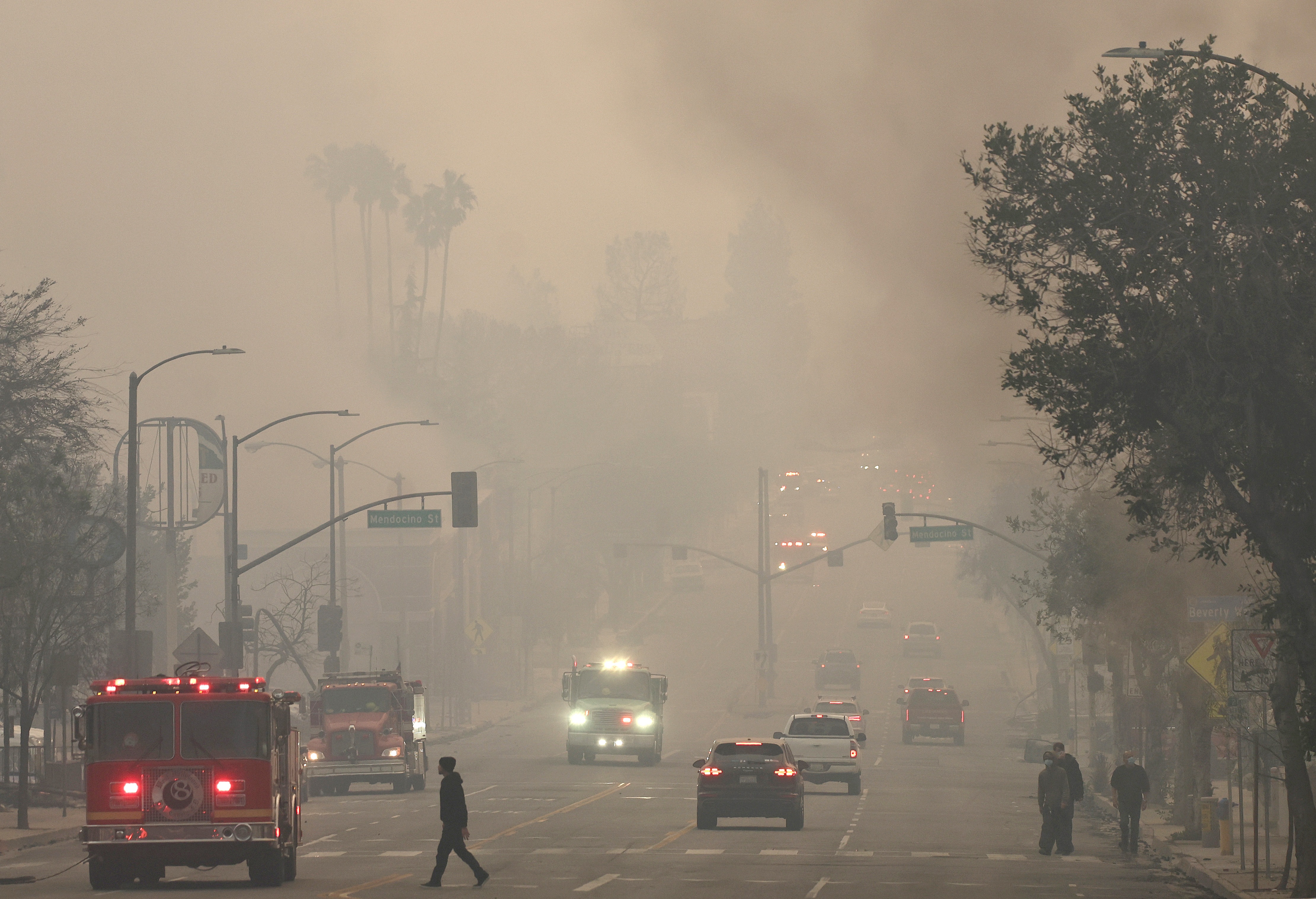 People walk through wildfire smoke in in Altadena, Calif., on Wednesday, as wildfires in Los Angeles County sharply worsened poor air quality.