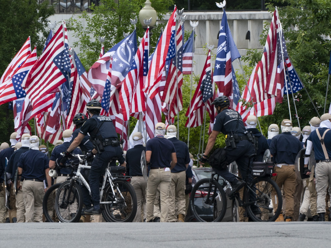 Holding upside-down U.S. flags, marchers with the white supremacist group known as the Patriot Front, chanted the phrase 
