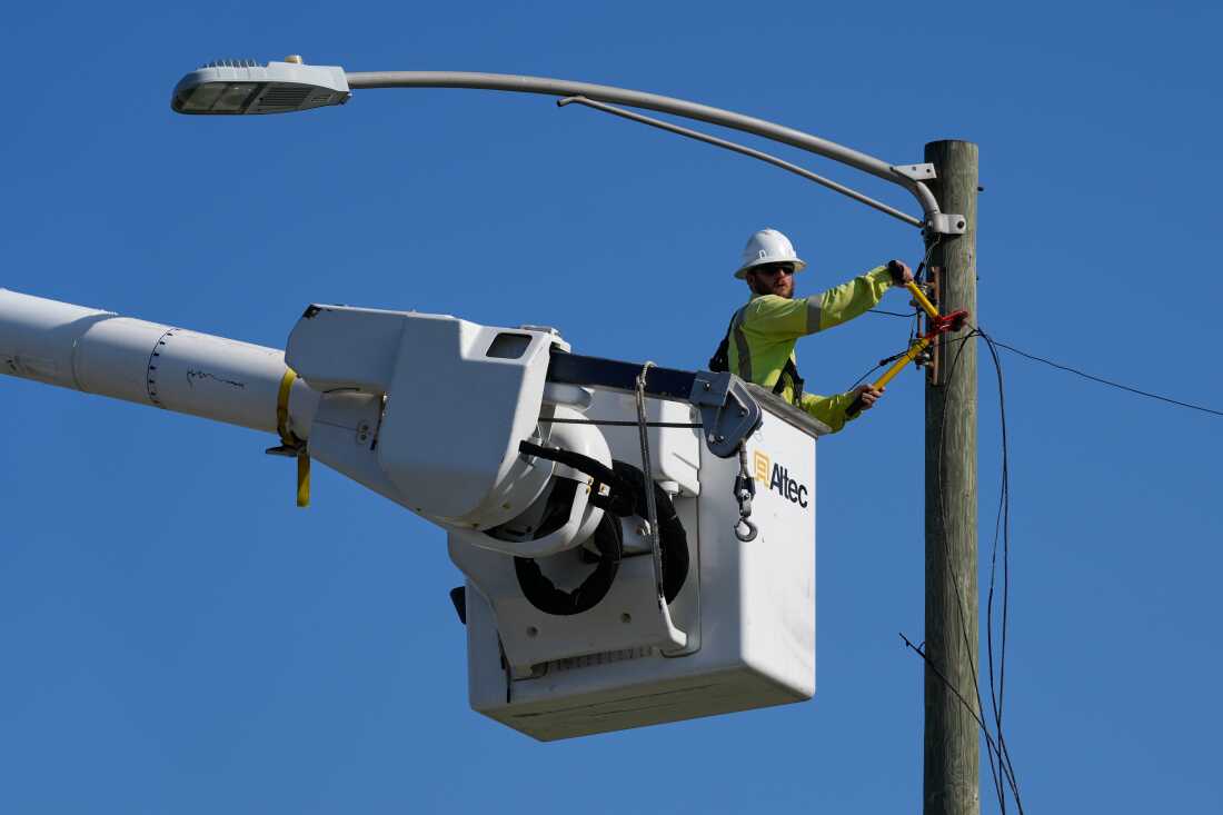 An electrical worker repairs power lines along a street in Gary, Ind, Thursday, Aug. 20, 2026, more than a week after a deadly storm passes through the area