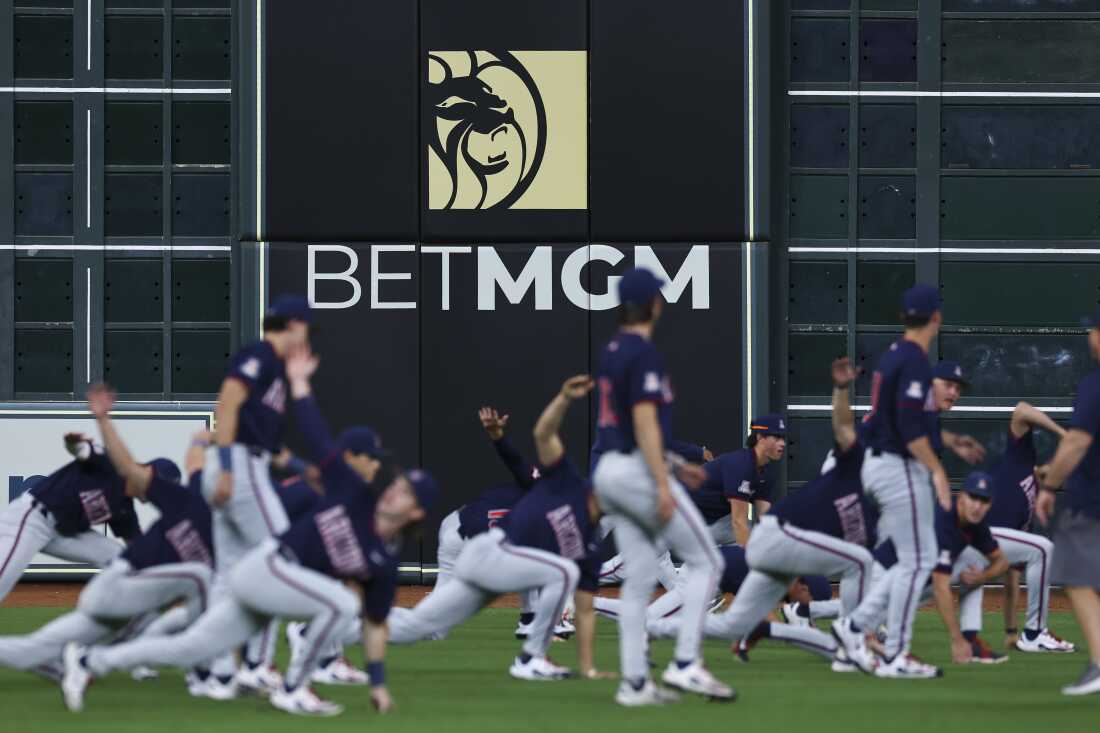 A baseball team is shown warming up in front of a huge advertisement for BetMGM.